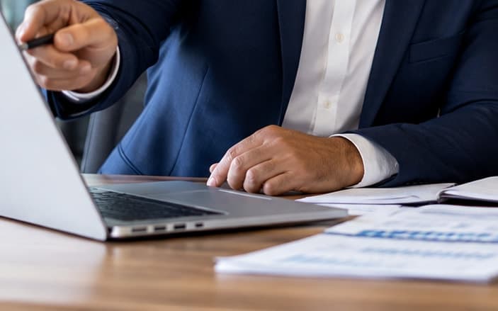 A specialist pointing out a plan on a laptop beside printed figures