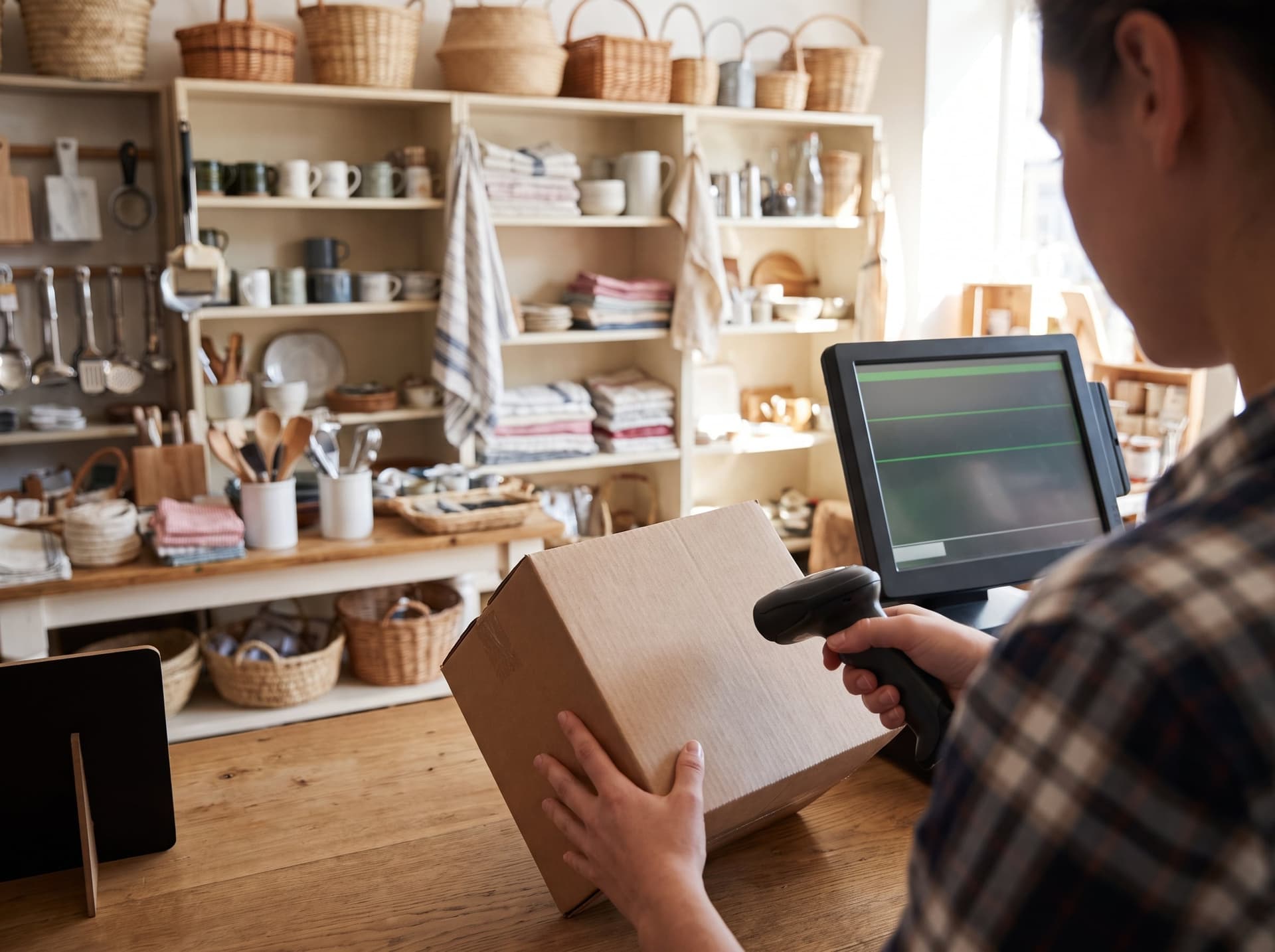 A clerk scanning a boxed item at a general store counter beside the POS
